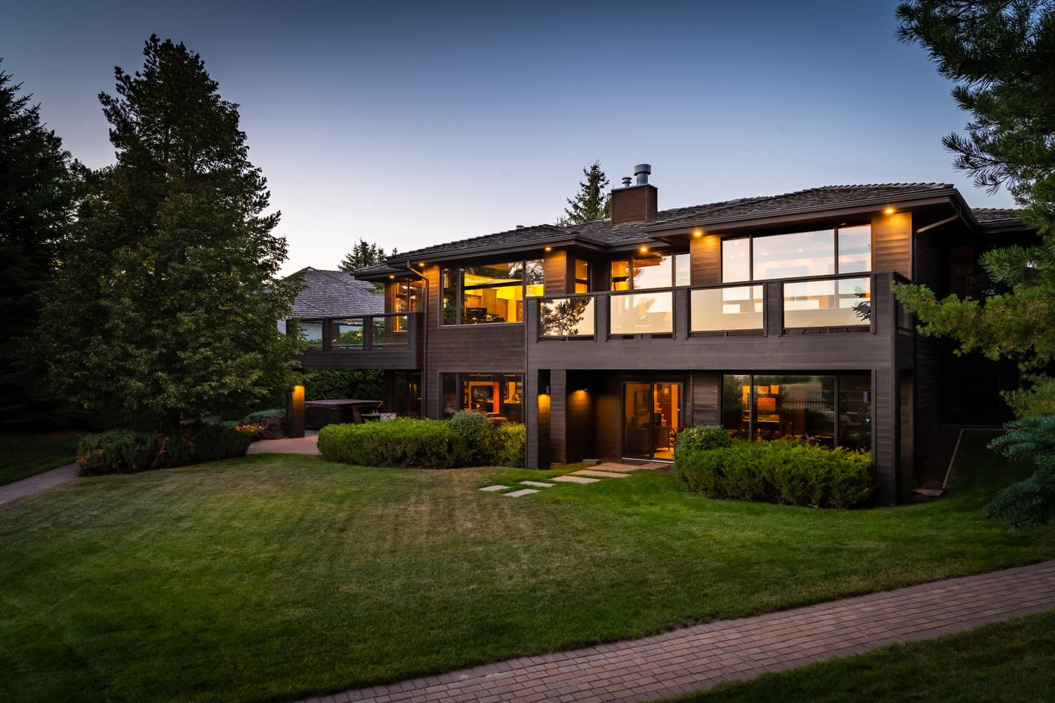 Modern wood-clad home exterior at twilight with landscaped yard