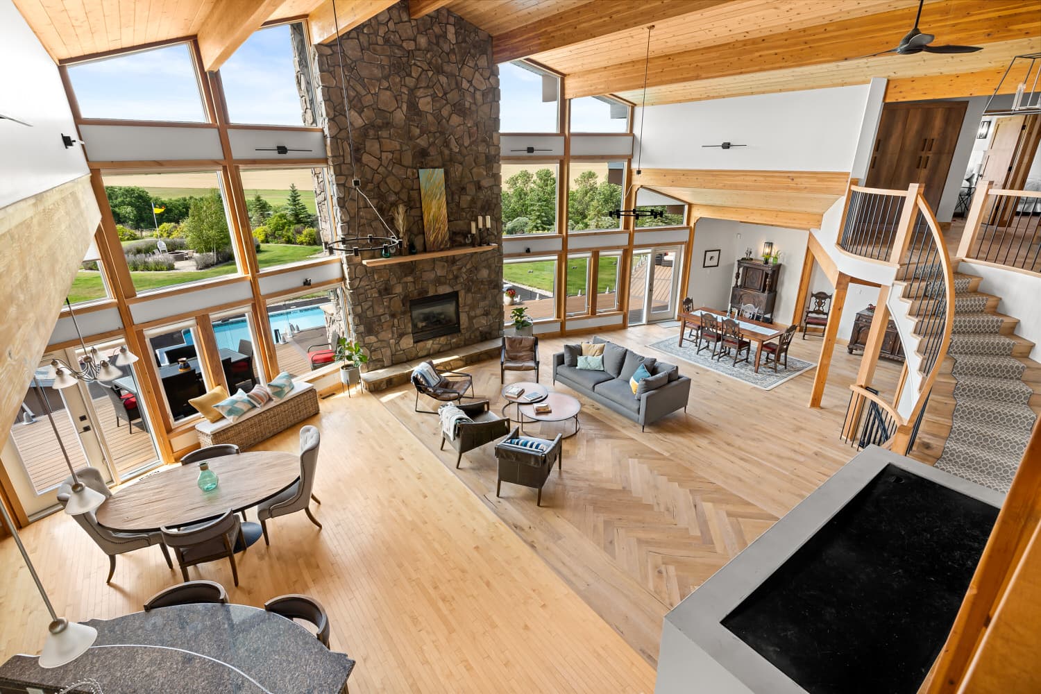 Vaulted timber great room with stone fireplace and pool view