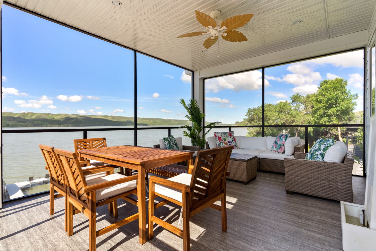 Screened-in lakefront sunroom with dining and lounge areas