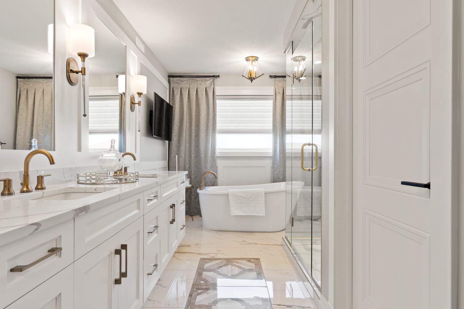 Elegant white ensuite with marble floors and brass fixtures
