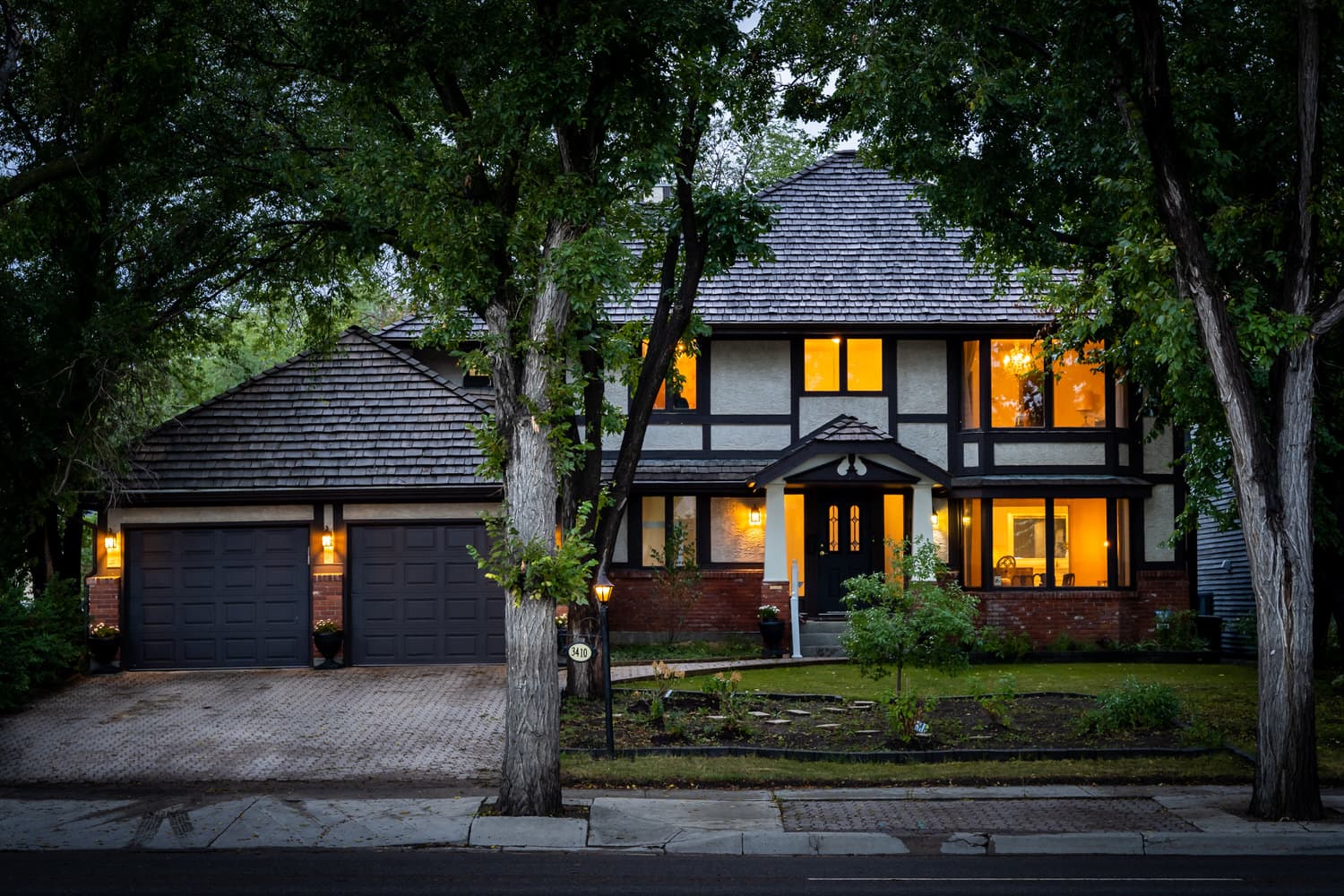 Tudor-style home exterior at twilight with warm interior glow